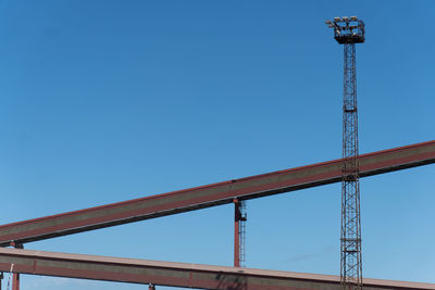 Low angle view of crane against clear blue sky