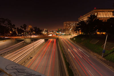 Light trails on highway in city against sky at night