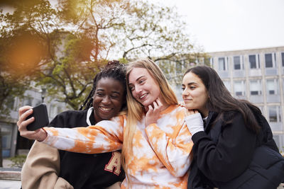 Three young female students taking selfie at campus