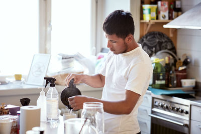 Young man preparing coffee in kitchen