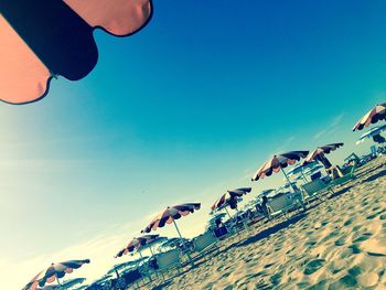 Low angle view of people at beach against clear sky