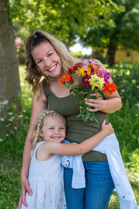 Portrait of happy girl embracing mother outdoors