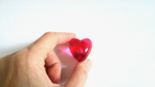 Close-up of hand holding strawberry over white background