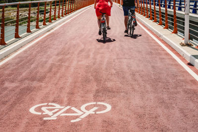 Low section of friends riding bicycles on road