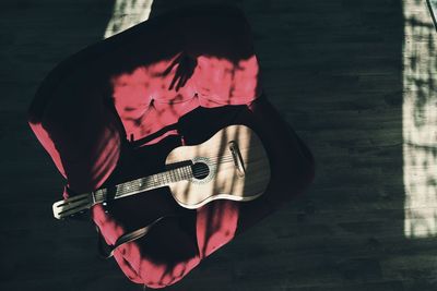 High angle view of guitar on chair over hardwood floor at home