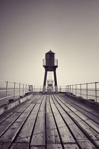 Tower on pier by sea against clear sky