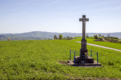 Traditional cross on field against sky