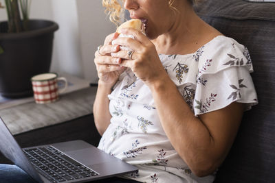 Midsection of woman drinking coffee at table