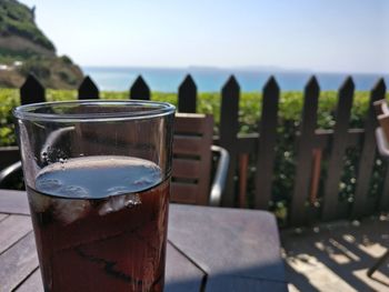 Close-up of beer glass on table against sea