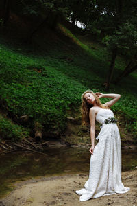 Beautiful woman in white dress standing at lakeshore