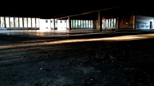 Empty road by abandoned building in city