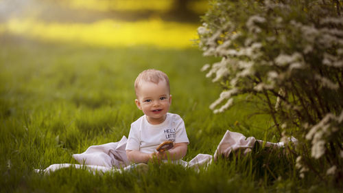 Little boy sitting on the grass and smiling