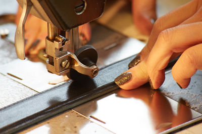 Cropped hands of woman using sewing machine