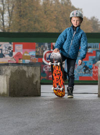 Portrait of boy with skateboard at park