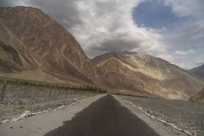 Scenic view of road by mountains against sky