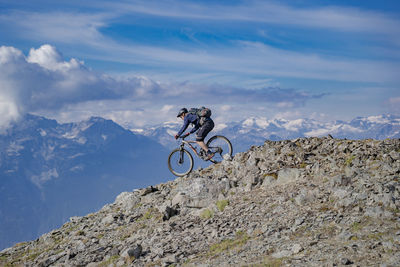 People riding bicycle on rock against sky