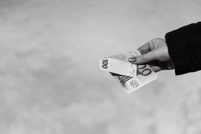 Cropped hand of man holding bitcoin against sky