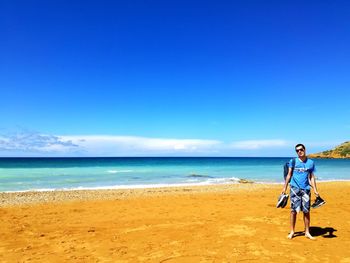 Full length of woman on beach against blue sky