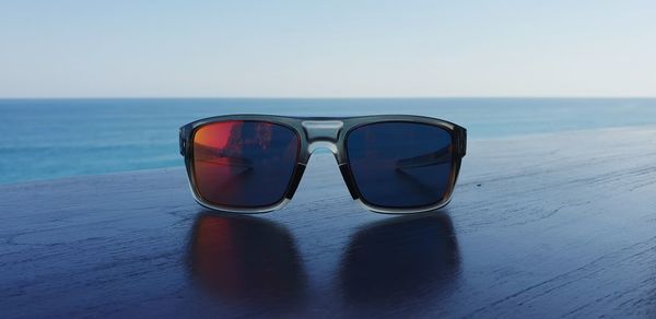 Sunglasses on table at beach against clear sky