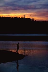 Silhouette person by tree against sky during sunset