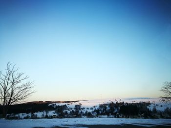 Scenic view of snowy field against clear sky during sunset