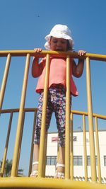 Low angle view of girl playing on playground against clear sky