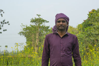 Young man looking away against plants