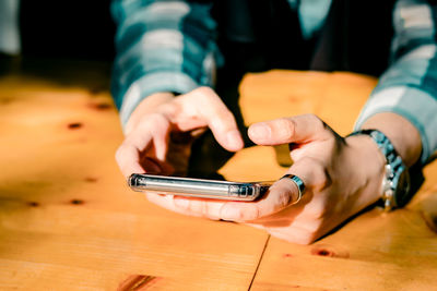 Midsection of man using mobile phone on table