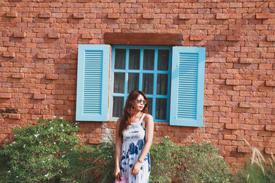 Low section of woman standing against brick wall