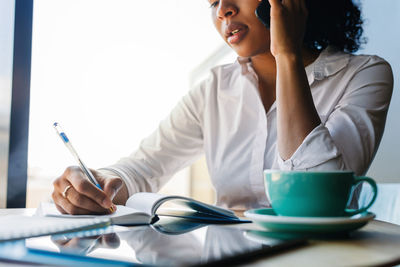 Midsection of woman sitting with umbrella on table