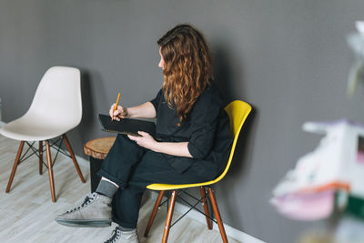 Charming adult woman middle aged woman with curly hair designer with drawing plan in hands in office 