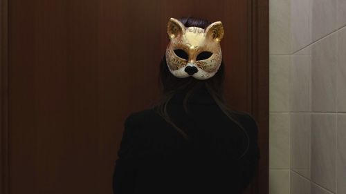 Rear view of woman wearing mask against wall