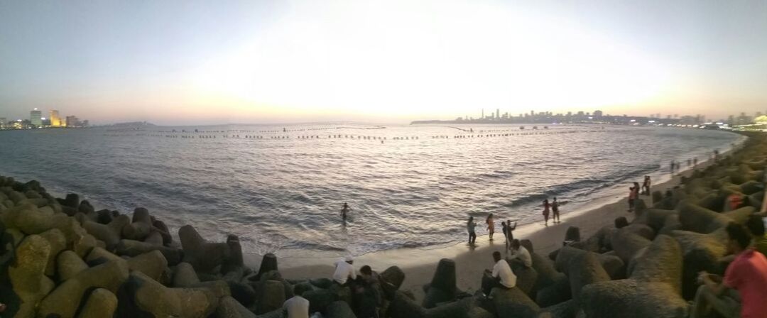 PANORAMIC VIEW OF PEOPLE AT BEACH AGAINST SKY