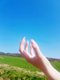 Midsection of person hand on field against clear sky