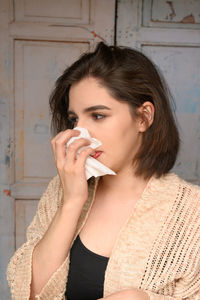 Close-up of woman covering nose with tissue