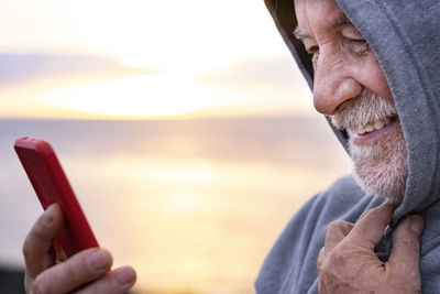 Smiling senior man looking at smart phone