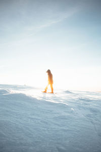 Woman hiking in snow against sky