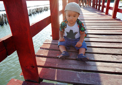 Cute baby boy sitting on footbridge
