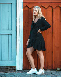 Full length portrait of woman standing against wall