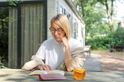 Woman reading book while sitting outdoors