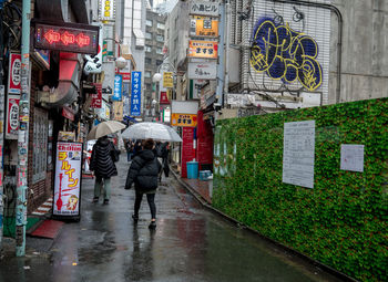 Rear view of people walking on wet street during monsoon