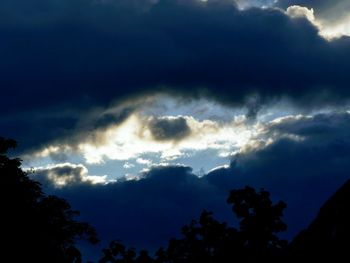 Low angle view of silhouette trees against dramatic sky