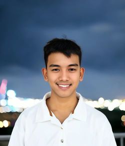 Portrait of smiling young woman standing against black background