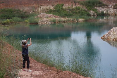 Rear view of woman photographing in lake