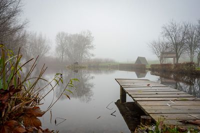 Scenic view of lake against foggy sky