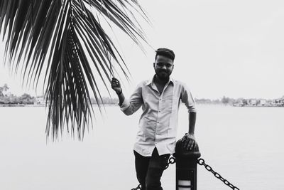 Young man standing against sea against clear sky