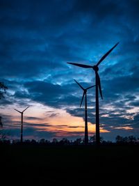 Low angle view of wind turbines on field against sky