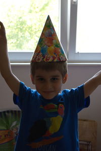 Portrait of cute boy wearing party hat at home