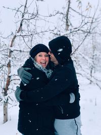 Couple embracing while standing in snow