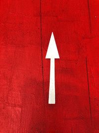 Close-up of arrow sign on red wall